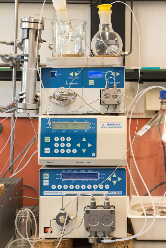 Präparative HPLC-Anlage mit mehreren KNAUER-Modulen, Glasgefäßen und verbundenen Schläuchen in einem Labor.